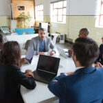 Confident leader talking to subordinates. Concentrated workers sitting at table and listening boss. Business meeting concept